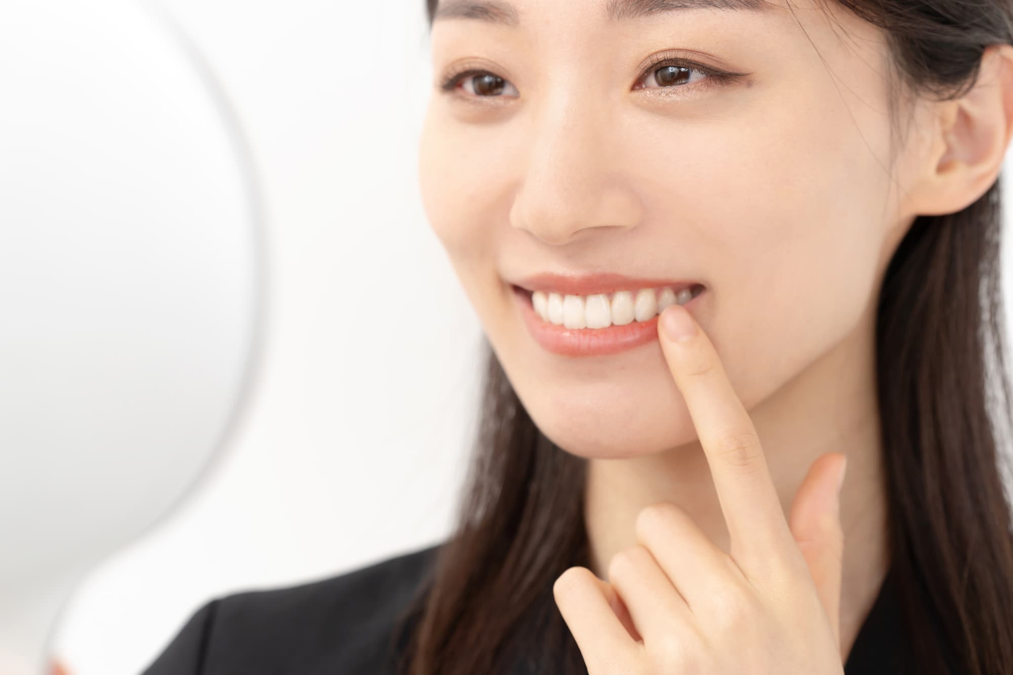 インプラント治療をした歯を指さして笑顔を見せる女性