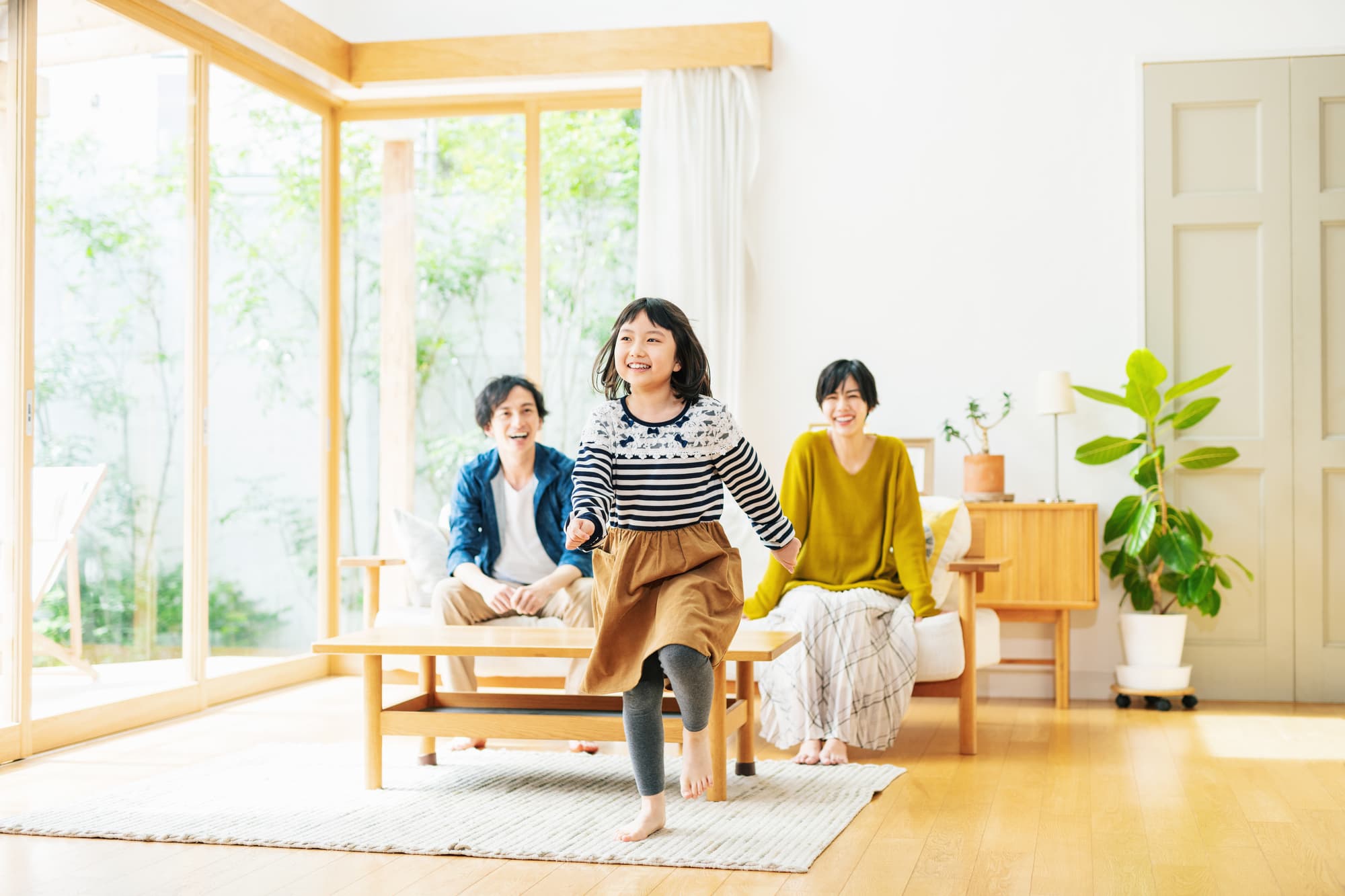 リビングで走る女の子と見守る両親