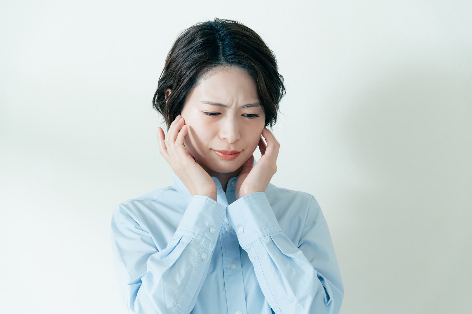 両方の顎関節を気にして触る女性