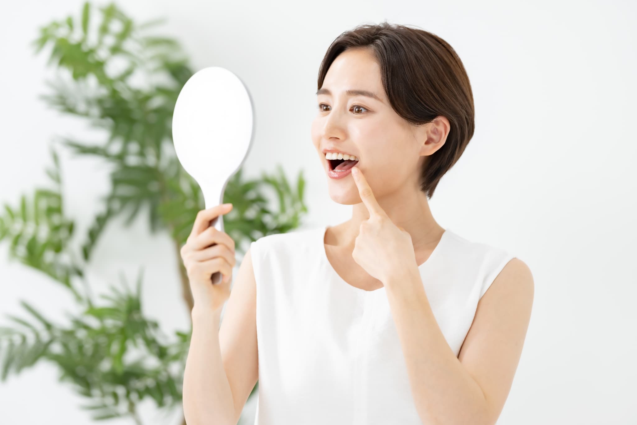手鏡で自分の奥歯を見る女性